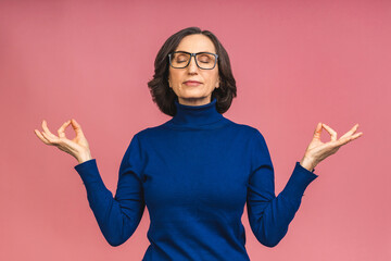 Smiling elderly mature senior woman lady holding hands in yoga gesture relaxing meditating, trying...