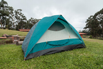 green tent set up on grass with trees in the background, pastime in the middle of nature, exterior and lifestyle, objects for camping