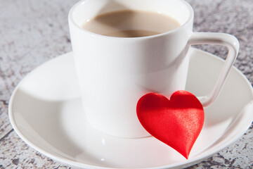 A mug of coffee and red heart on a glass saucer