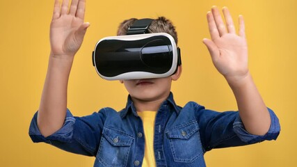 Child boy wearing virtual reality goggles raising hands cyberspace immersion isolated orange studio