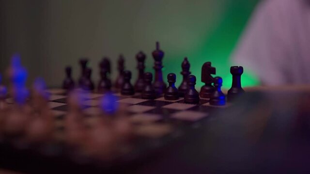 A boy in a white T-shirt is playing chess