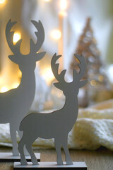 Two wooden reindeer figurines and bokeh lights in the background. Selective focus.