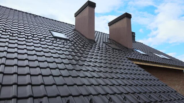 Closeup snow guard for safety in winter on house roof top covered with ceramic shingles. Tiled covering of building