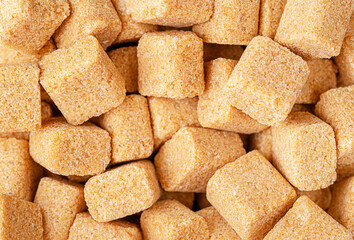 Brown cane sugar cubes background. Closeup, overhead.