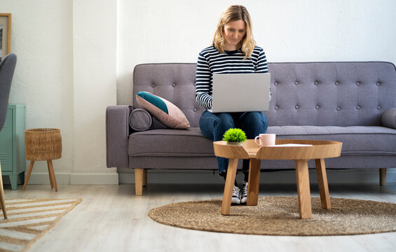 Woman using laptop while sitting on sofa at home