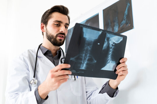 Male medical expert examining X-ray report while standing by white board
