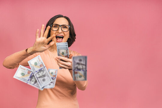 Happy Winner! Image Of A Mature Senior Happy Old Woman Standing Isolated Over Pink Background, Holding Money.