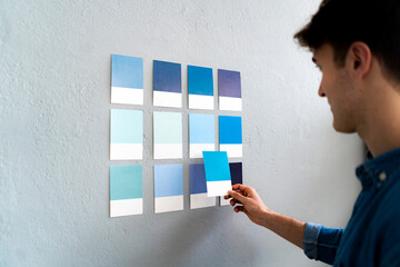 Male entrepreneur selecting blue cards on wall