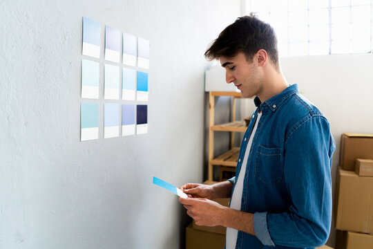 Businessman looking at blue card in front of wall at warehouse