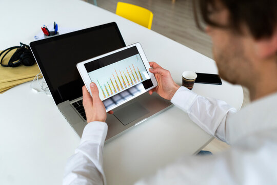 Male entrepreneur checking graph on digital tablet while working at office