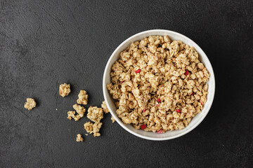 Granola in white bowl on dark table.