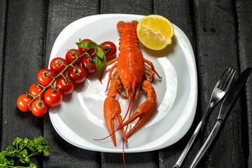 large boiled crayfish on a white plate with a cherry tomato branch and lemon flatley
