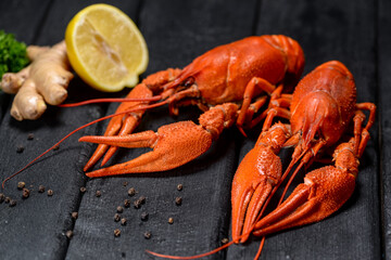 two large boiled crayfish on a black background with ginger and lemon
