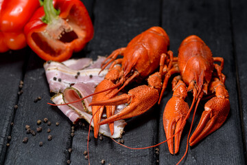 two large boiled crayfish with bacon and paprika on a black background
