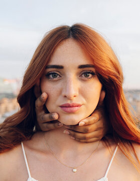 Redhead young woman with hands of female friend covering her neck