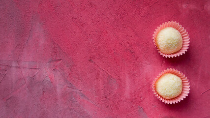 Two delicious candies (White Chocolate Coconut Truffle) on a pink and gray background. There is free space for text (copy space). Can be used as a valentine card. Romantic concept.