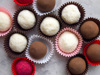 Top view on tasty chocolate truffles. Different variants of candy: white coconut truffles, cocoa truffles and pink raspberry bonbon.