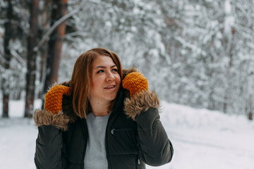 Portrait of a happy girl with a short haircut in mustard mittens in the forest after a snowfall . Christmas holidays, outdoor activities