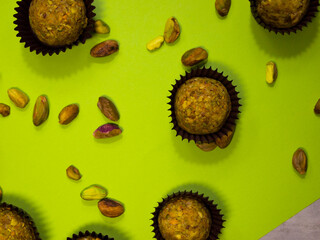 Top view on pistachio chocolate truffles on a light green background. Next to the candy are nuts. Closeup.