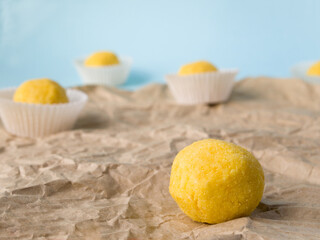 Side view of white chocolate truffles coated with citrus powder. One truffle without candy wrapper, the rest with.