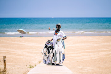 Male vendor standing on boardwalk while selling clothes at beach during sunny day