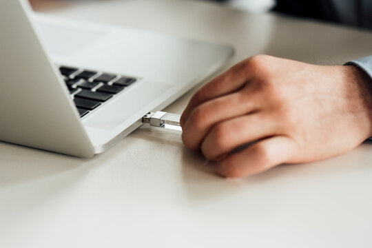 Businessman Putting Pen Drive In Laptop On Desk