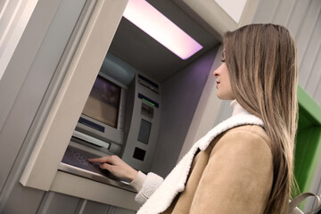 Fototapeta na wymiar Young woman entering cash machine pin code outdoors