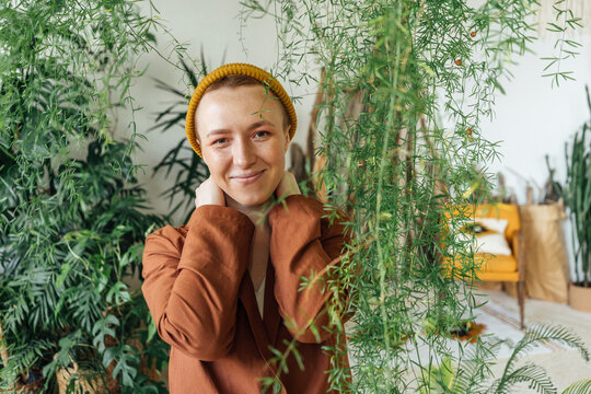 Smiling businesswoman wearing knit hat by plants at green office