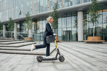 Businesswoman riding electric push scooter in office park