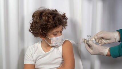 Europe, Italy, Milan - Vaccination against Covid-19 Coronavirus for children in pediatric age 5 to 11 years - pro vax and no vax with generic vaccine vial - Doctor make vaccine to boy with mask