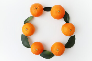 Manadrins lie with leaves in a circle on a white background