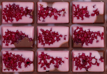 Homemade pink milk chocolate bar with dried berries (strawberry, raspberry, cranberry, cherry) close-up. Top view. Selective focus