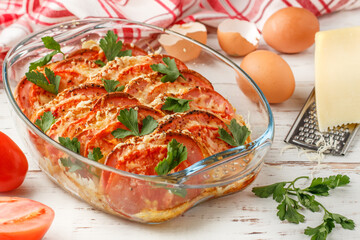 Bread casserole with sausage, cheese, tomatoes, eggs and parsley. Breakfast. Brunch. Delicious homemade food on a white wooden background. Selective focus