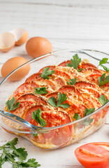 Bread casserole with sausage, cheese, tomatoes, eggs and parsley. Breakfast. Brunch. Delicious homemade food on a white wooden background. Selective focus, copy space
