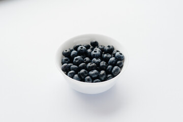 Beautiful ripe blueberries in a glass bowl on a white background. Healthy food, and vitamins.