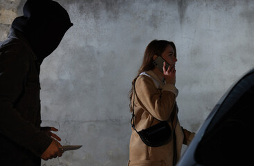 Man with knife stalking young woman while she talking on phone near car