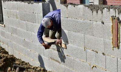 The mason screws a wood plank into the wall at the construction site before concreting
