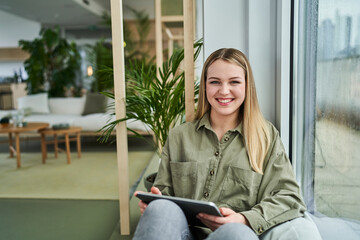 Happy female trainee sitting with digital tablet at office
