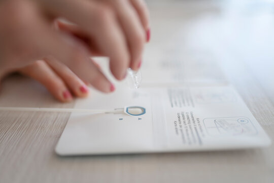 Woman taking COVID-19 rapid test with diagnostic tool at home