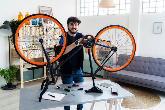 Smiling Man Repairing Bicycle At Home