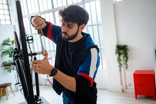 Man fastening screw of bicycle with wrench at home