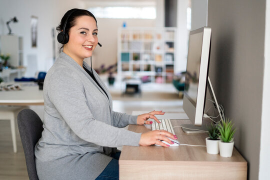 Smiling female customer service representative using computer while working at home office