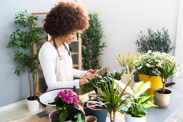 Female florist photographing plant through mobile phone at shop