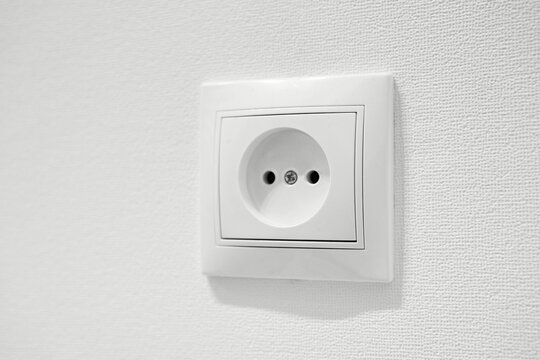 Common cheap plastic AC power wall outlet. German circular recess socket with two round holes for 2 pins europlugs types C, E and F. Not grounded European white electrical socket CEE 7 against wall