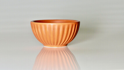 Small terracotta pot and reflection against white background with copyspace