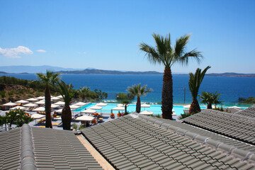 Fototapeta premium View from the gray roof of the swimming pool near the sea. Near the pool there are sun loungers and umbrellas.