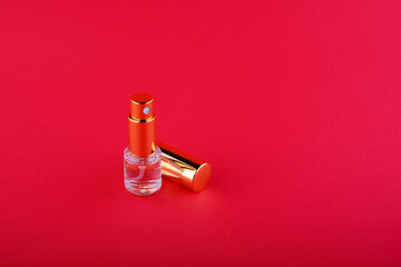 bottle with liquid with a golden cap that lies next to it on a red background