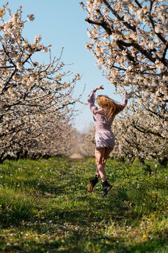 Carefree woman dancing in orchard during springtime