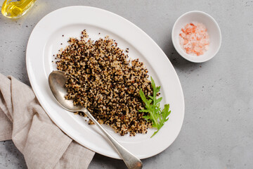 Portion of cooked quinoa white, red and black in white plate on grey rustic background, top view, place for text recipes or menu. Vegan Superfood, healthy eating and nutrition or diet concept.