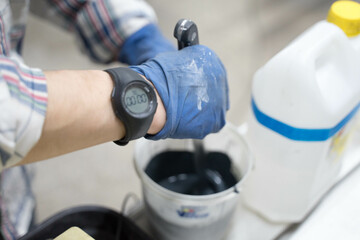 a man pours paint into a plastic can